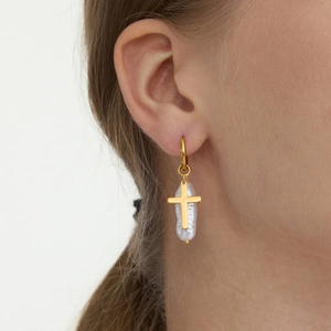 Close-up of model wearing baroque pearl and gold cross pendant hoop earrings