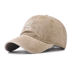 Close-up of white embroidered cartoon bear on khaki washed cotton baseball cap