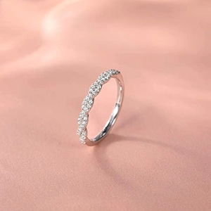Macro view of interwoven wavy silver ring band with pave set small diamonds on satin