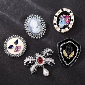 Detailed flat lay of luxury vintage brooches with pearls and rhinestones on black background