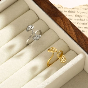 Close-up of gold and silver ginkgo leaf rings in a wooden velvet jewelry box
