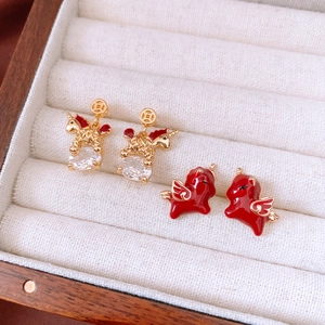 Detailed shot of 18k gold plated unicorn and red winged pegasus earrings in a jewelry box