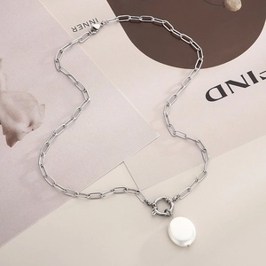 Macro detail of silver link chain necklace with large round white pearl pendant and OT buckle