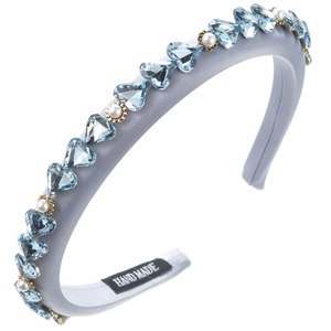 Close-up of thick blue headband featuring heart-shaped crystals and small white pearls