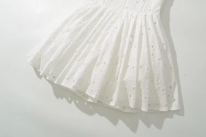 Détails de la broderie ajourée blanche et de l'ourlet sur une mini-robe avec col en V