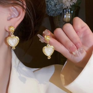 Close-up of vintage gold heart earrings with white shell inlay and crystal trim