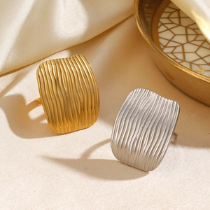 Modern 18K gold plated rectangular rings with wave texture on satin background