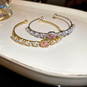 Detailed macro view of gold and silver open bracelets with pink oval zircons
