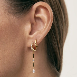 Détail de boucles d'oreilles pampilles dorées avec zircon incrusté portées par un mannequin