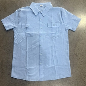 Flat lay of light blue short sleeve linen shirt with lapel collar and double chest pockets