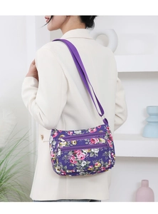 Detail of purple floral shoulder bag with adjustable strap and multiple zipper pockets