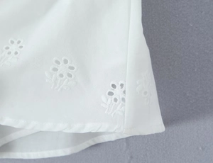 Vue macro détaillée de la dentelle blanche brodée et des coutures fines sur le vêtement