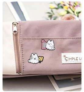 Detail of cute cat enamel pins playing music on a lavender and beige canvas storage bag