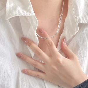 Detail of 925 silver asymmetric necklace with round beads and oval links on white shirt