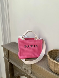 Detailed view of pink knitted tote bag with Paris embroidery on a rustic fireplace