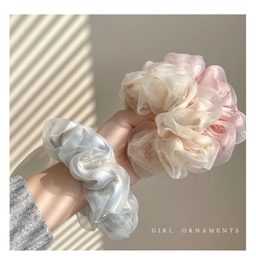 Dettaglio di elastici in organza a fiori nei toni pastello blu, beige e rosa