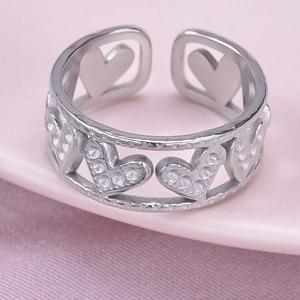 Macro shot of silver open ring with hollow heart patterns and textured details