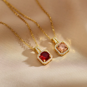 Detail view of square gold pendants with red and champagne stones on silk background