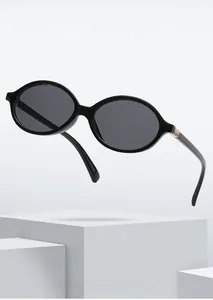 Detail of oval black sunglasses featuring vintage gold metal hinge and simple frame
