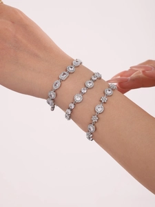 Dettaglio di tre braccialetti d'argento a strati con zirconi e delicati motivi a fiori