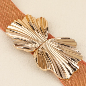Elastischer orangefarbener Gürtel mit goldener Muschelschnalle und polierter Metalltextur