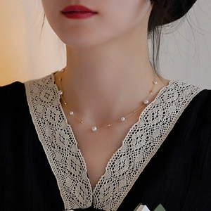 Detail showing natural white pearls and gold beads on a delicate chain around a woman's neck