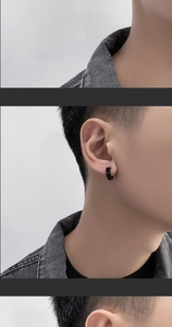 Macro detail of a classic black stainless steel clip-on hoop earring on a male ear
