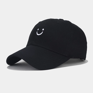 Detail of white smiley face embroidery on a black cotton twill baseball cap