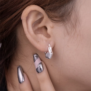 Close-up of minimalist silver hollow U-shaped geometric earrings on a model's ear