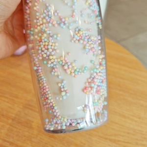 Close-up of double-layer plastic cup filled with colorful foam balls and liquid