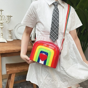 Detailed shot of a rainbow arc crossbody bag featuring a glossy red heart and webbing strap