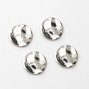 Close-up of four silver alloy round pendants with 'things to come' script for DIY jewelry