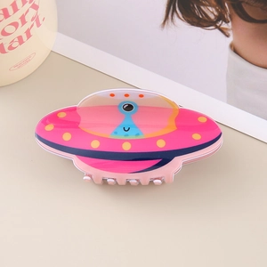 Macro view of UFO-shaped hair claw clip with colorful alien pattern on acrylic finish