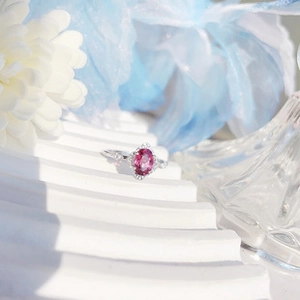 Dettaglio anello in argento con opale rosa ovale su un piedistallo bianco a onde