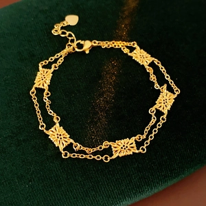Macro shot of gold vintage flower bracelet with intricate hollowed petals on green fabric