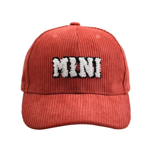 Close-up of MINI embroidery on dark red corduroy baseball cap with striped texture