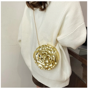 Detail of golden metallic rose clutch bag with layered petals and fine chain strap