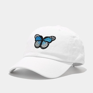 Détail de broderie papillon bleu sur casquette de baseball en coton blanc avec visière courbée