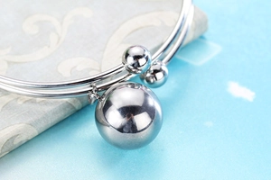 Macro detail of silver double-band cuff bracelet featuring a large polished metal sphere