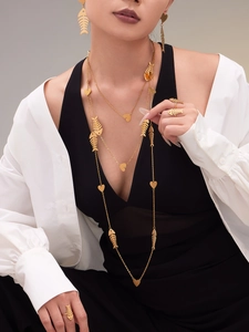 Elegant gold fishbone and heart jewelry set featuring layered necklaces and rings on model
