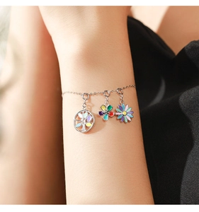 Macro view of silver bracelet with colorful enamel tree of life and floral pendants