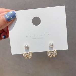 Detailed view of elegant bowknot earrings featuring white pearls and sparkling zircons