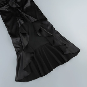 Detail of elegant black satin dress featuring asymmetrical ruffled hem and silk texture