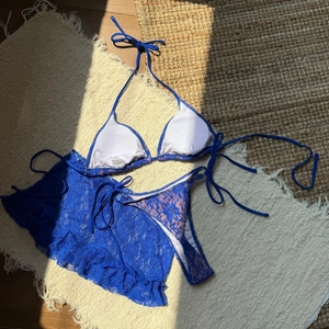 Détail du bikini en dentelle bleue avec volants et étiquette de taille S posé à plat