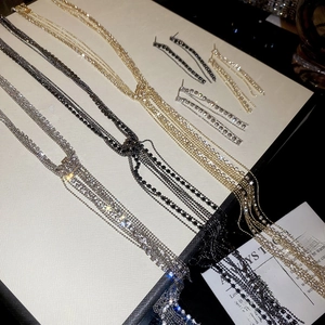 Dettaglio dei set collana a strati con nappe e orecchini in argento, oro e nero lucido