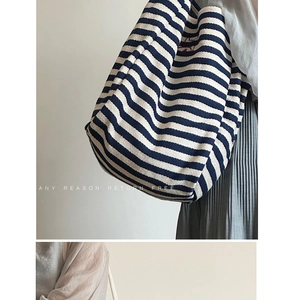 Close-up of blue and white striped canvas tote bag with woven rope handles and embroidery
