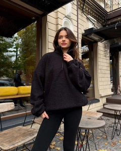 Close-up of black sherpa fleece fabric texture on half-zip oversized warm pullover