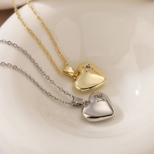 Gold and silver heart necklaces with star cutout and zircon on a ceramic tray