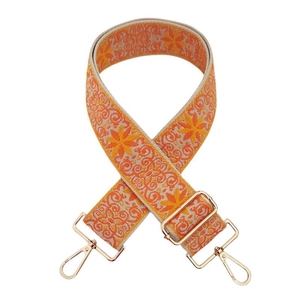 Detailed view of woven floral pattern shoulder strap with gold metal lobster clasps