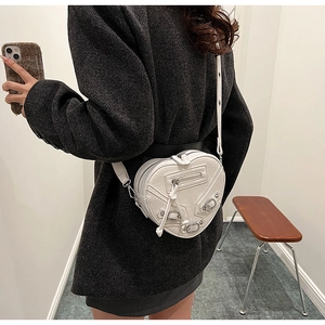 Détail du sac à bandoulière blanc en forme de cœur avec rivets et pompons en cuir